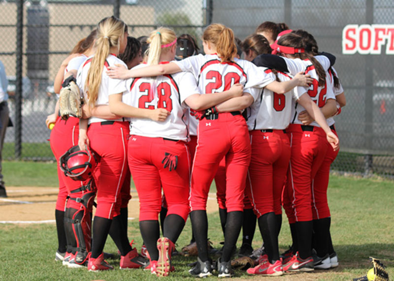 The Girls Varsity Softball team huddles before the start of the 1st inning.