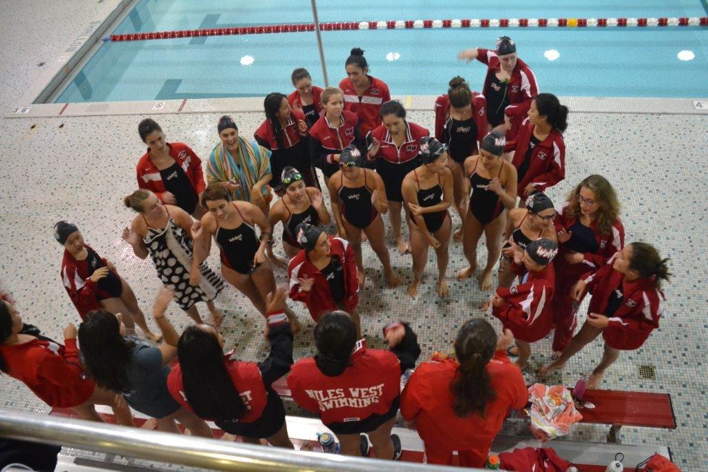 The girls swim team conversing during a meet. 