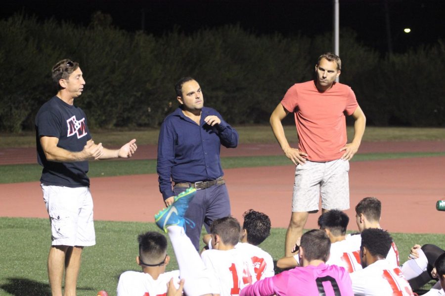 Assistant Coach Vasilios Papaioannou (far left) speaks to the varsity boys soccer team at half time during the 2017 season. Photo by Sarah Cohen. 