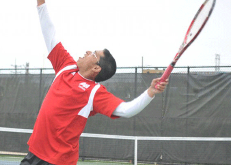 Tennis team member going up for a serve. 