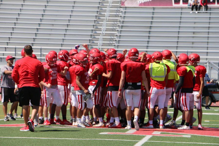 The football players circling up as they finish off the game. 