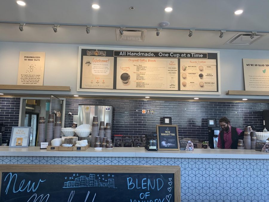 An overlook of the barista counter from the waiting line, with a complete display of the menu. 