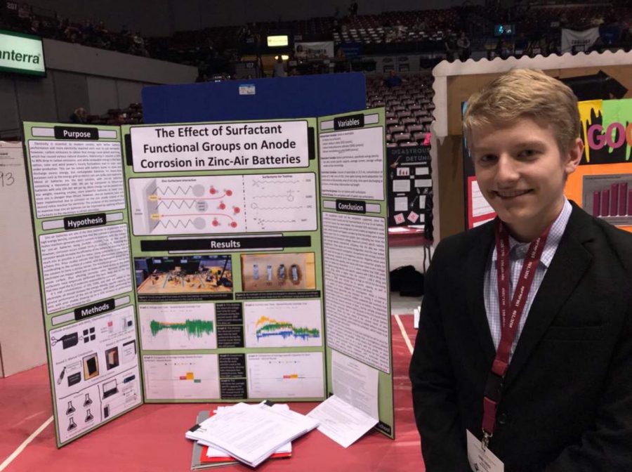 Senior Daniel Cudzich stands in front of his project at the science fair 