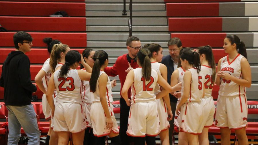 Varsity girls basketball huddle together during the time-out to discuss their defensive tactics. 