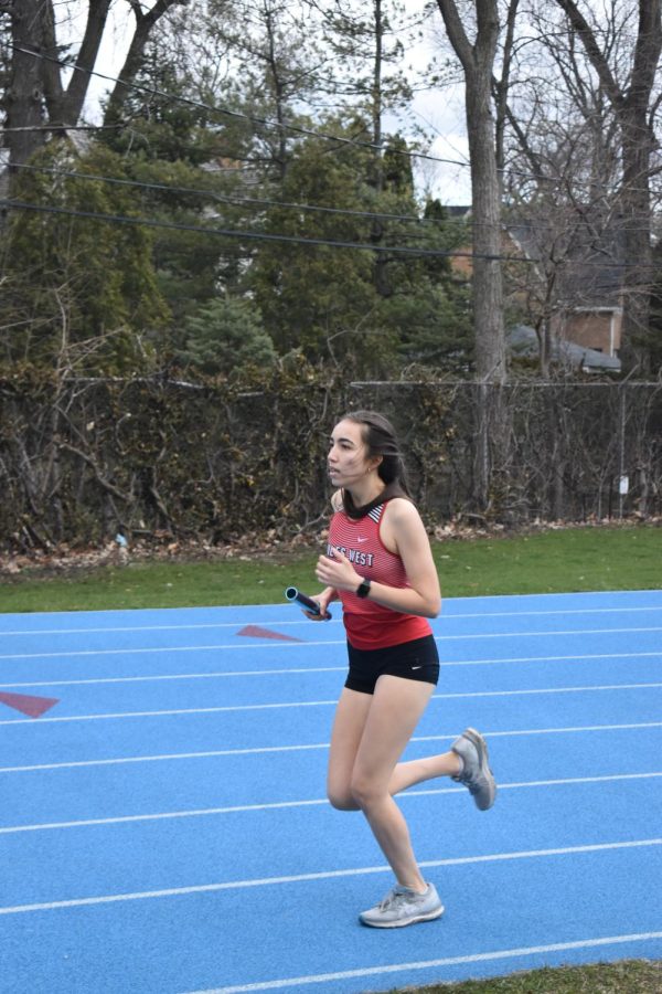 Emma Bennett running her second lab around the track after Melanie Sorisho passes her the baton in the 8 by 400 relay race.