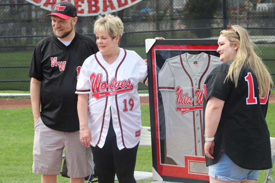 Beth Schwarz, his wife, and their kids smile for a picture with his framed jersey. 