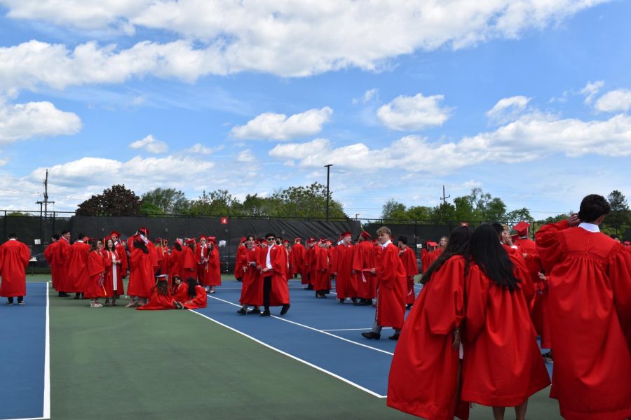 The graduates prepare and take pictures in the tennis courts.
