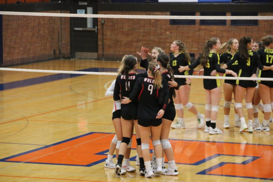 The volleyball girls huddle up after winning the point.