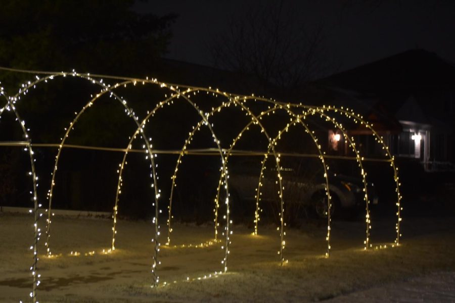 A lightup arched walkway surrounds the sidewalk in front of this house.