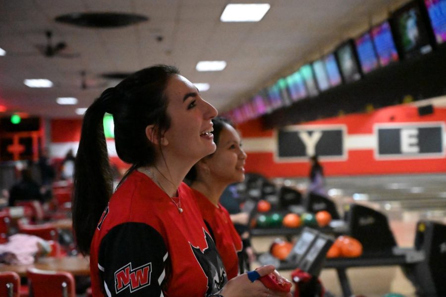 Senior Mia Sarris and Junior Xenia Haphziba Gonzales smile when their teammate makes a strike. 