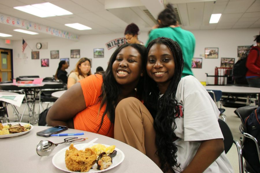 Seniors Ashley Kyobe and Cherie Animashaun smile after setting up the holiday party.