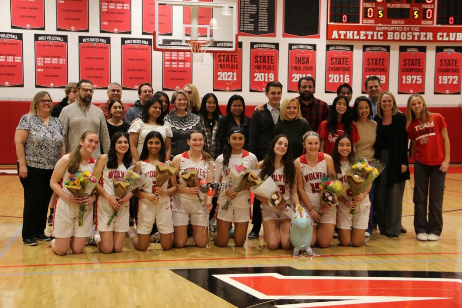 The eight seniors hold flowers while posing with their families.