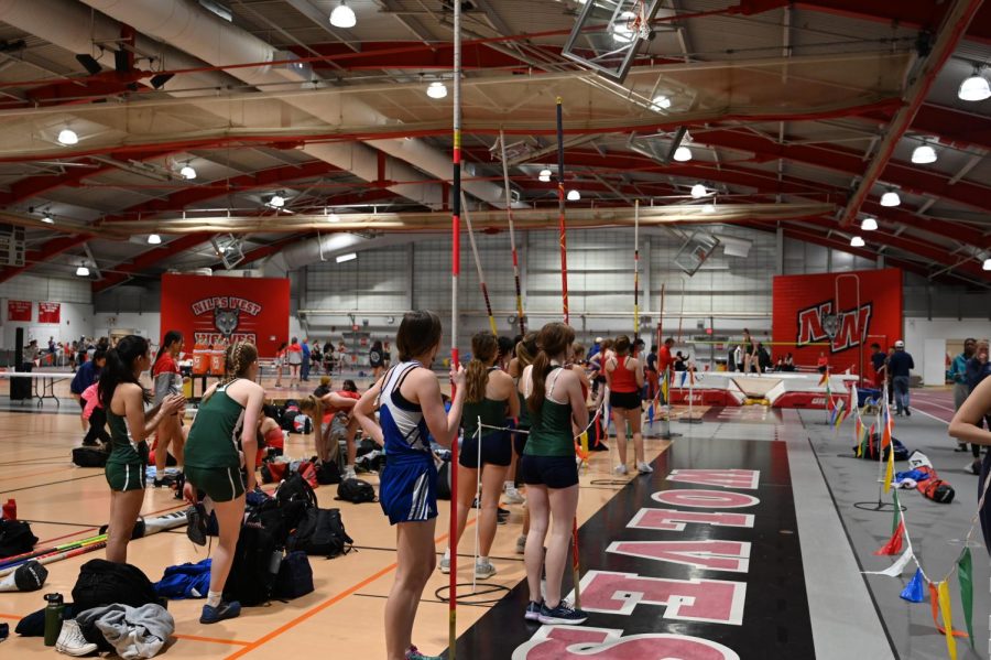 Pole Vaulters watch as some volunteers set up the bar.