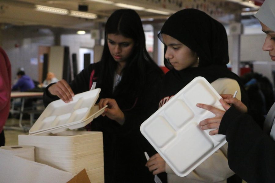 Amaani Syeda and Alina Abdulsamad pass out plates. 