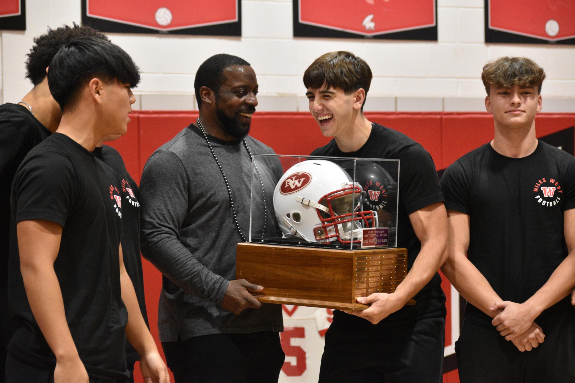 Mendenhall laughs with captain Aiden Delisi, senior, while holding the Skokie Skirmish trophy. 