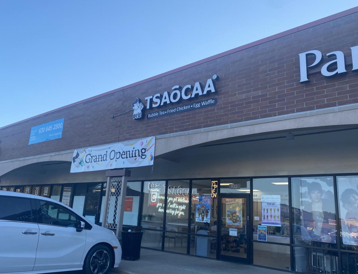 The exterior of Tsaocaa shows their Grand Opening banner and windows to see inside the shop. 