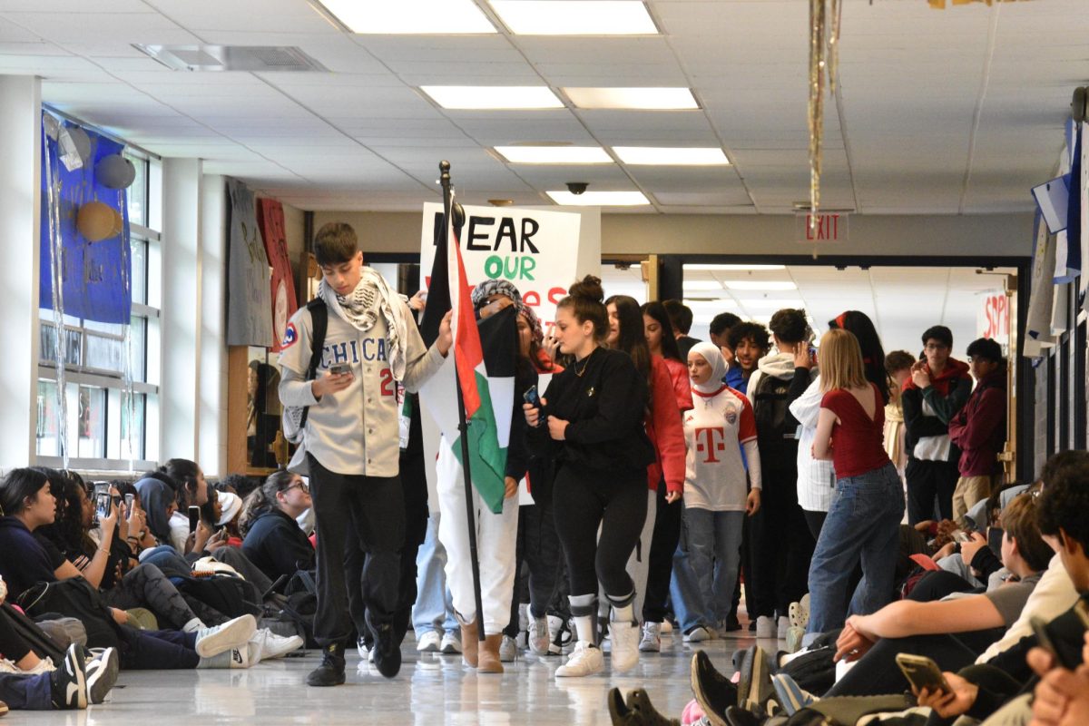 Students walk through the halls, holding signs and flags. 