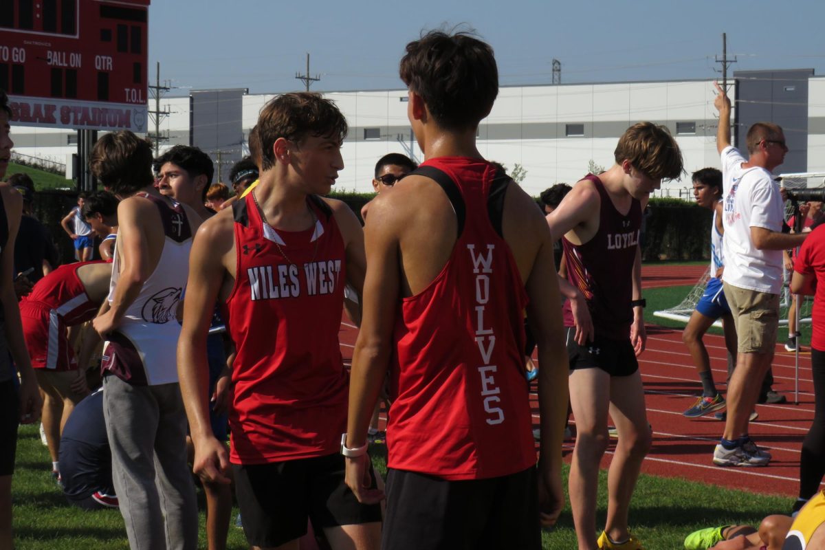 Jack Feldman and Angel Gomez exchange words after finishing their varsity race. Voices can be heard around the Niles West track as the runners conversate with their teammates to discuss their performances.