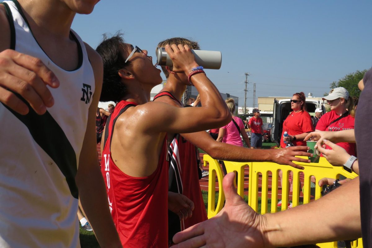 Daniel Lee, junior, takes a drink from his water bottle after a tiring varsity race. Other runners surrounding Lee reach for water bottles as well. 