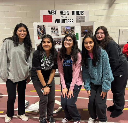 Raina Singh, in the middle, and other club members posing in front of a WHO poster during the club fair. 