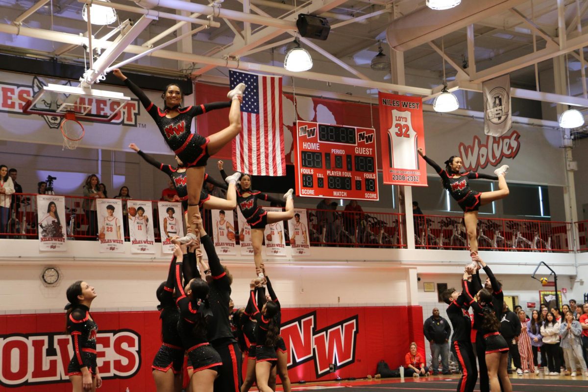 Niles West's varsity cheerleaders do an elite stunt with the fliers performing a scale. 