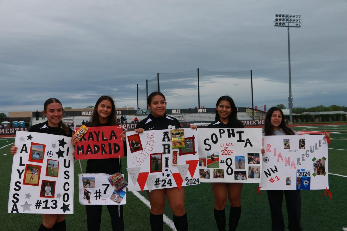 Niles West junior varsity seniors pose together in front of their signs.