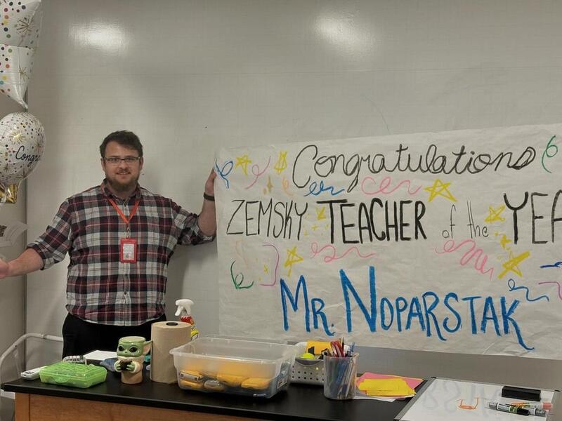 Physics Teacher Nathan Noparstak next to his banner