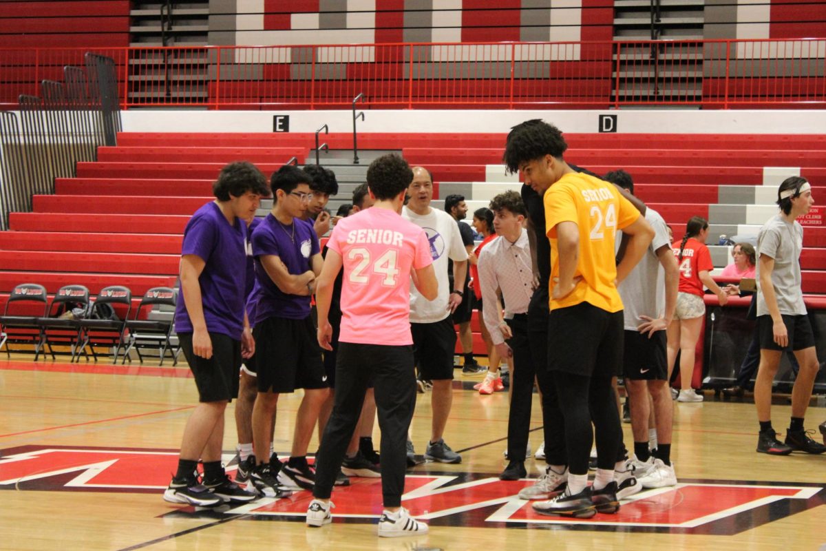 Members of the Purple, Orange and Gray, all student teams, gather around a die to determine which team would be playing who in the tournament. 