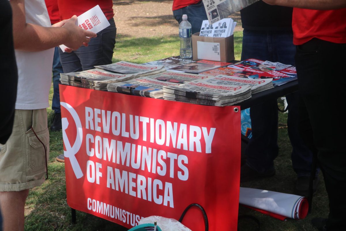 A table in the park set up for the Revolutionary Communists of America. The table is stacked with political pamphlets being passed out.