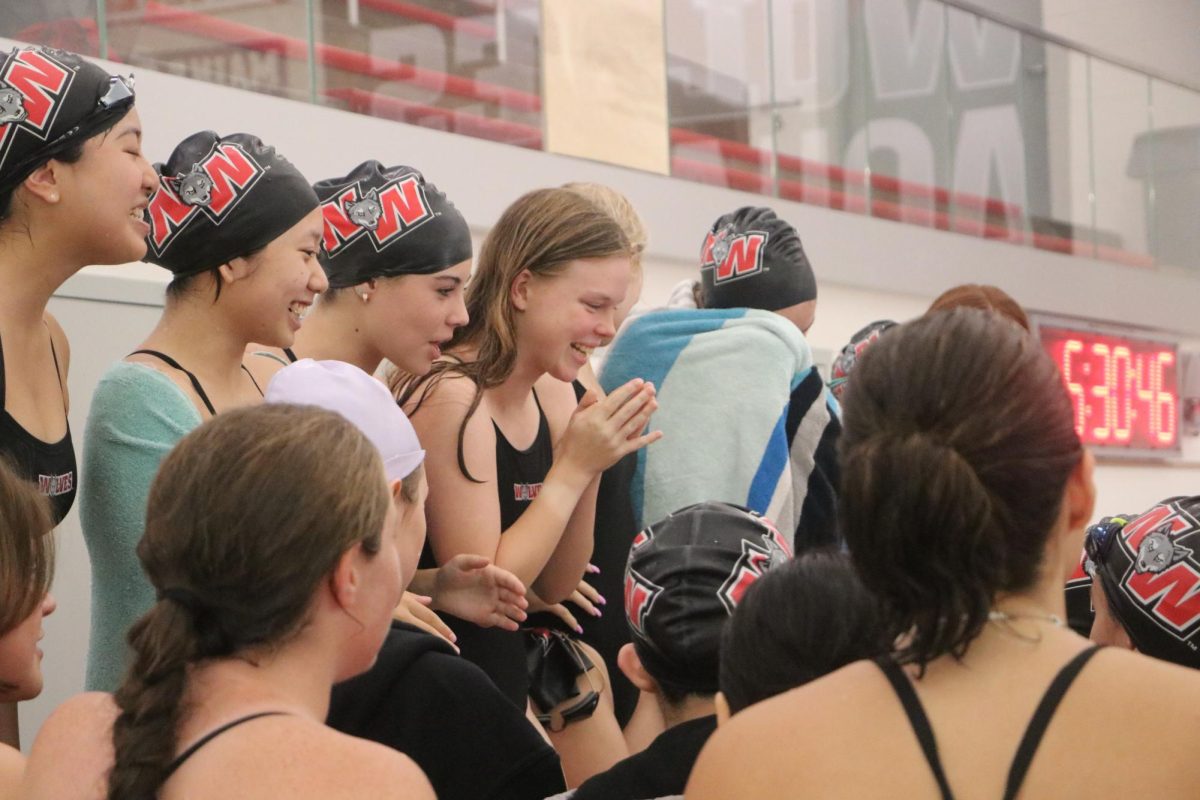 The swim and dive team stands together and cheers before the meets start. 