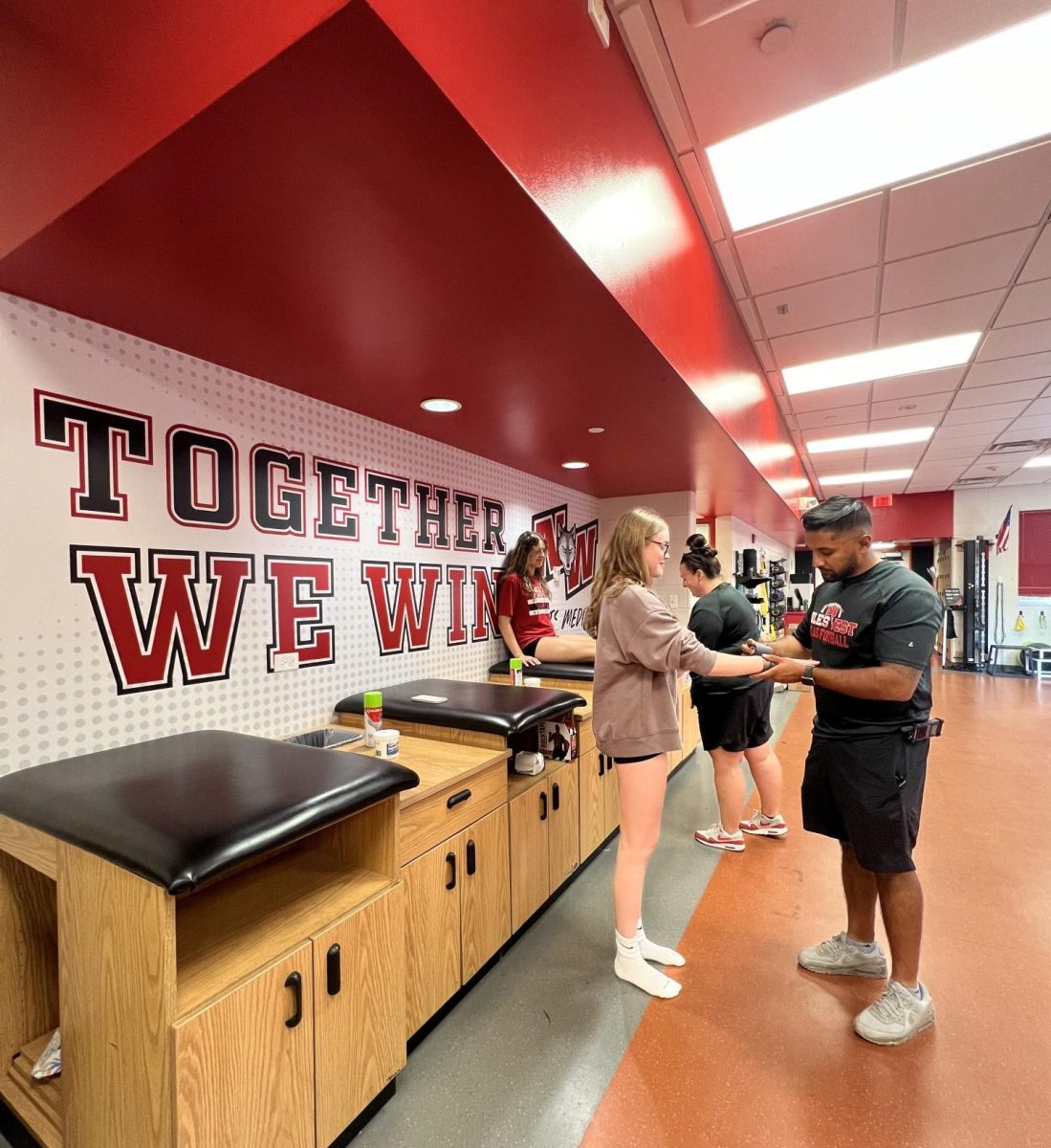 Trainers Nicole Tinetti and Zain Anjum wrap athletes before their practices. 