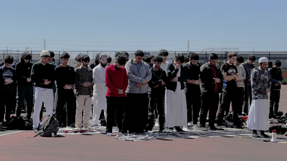 Students from the Muslim Student Association (MSA) pray together on prayer mats on the tennis courts.  They are facing the direction of the Kaaba, a place of worship located in Mecca, Saudi Arabia.  MSA meets Friday afternoons for prayer and discussion.