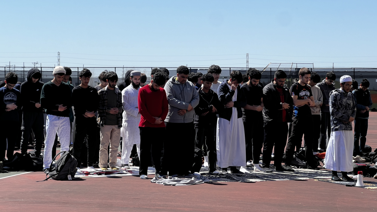 Students from the Muslim Student Association (MSA) pray together on prayer mats on the Niles West tennis courts.  They are facing the direction of the Kaaba, a place of worship located in Mecca, Saudi Arabia.  MSA meets Friday afternoons for prayer and discussion.