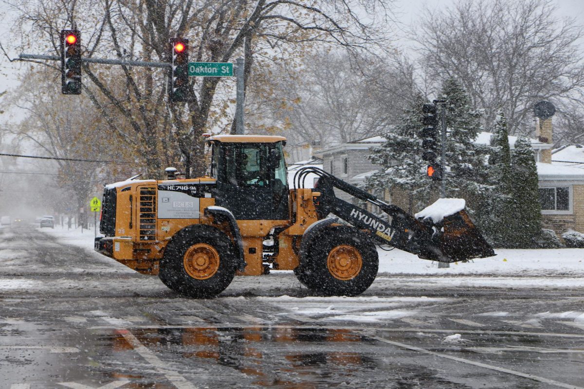 A snow plow drives down Oakton Street, adjacent to Niles West. 