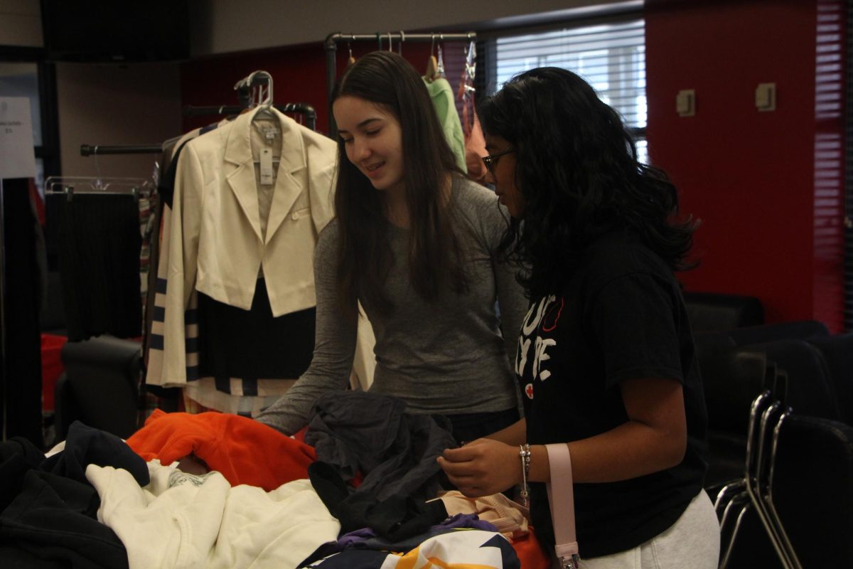 From left, seniors Anna Baesel and Nichelle Thomas rummage through the tables of clothing items. 