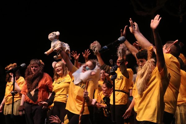 "Roar" cast waves their hands in the air as Rafiki holds up a plush Simba.