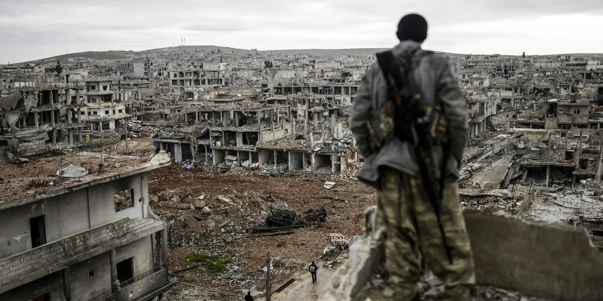 "A MAN STANDS ATOP A BUILDING LOOKING AT THE DESTROYED SYRIAN TOWN OF KOBANE, ALSO KNOWN AS AIN AL-ARAB, 2015." via history.com