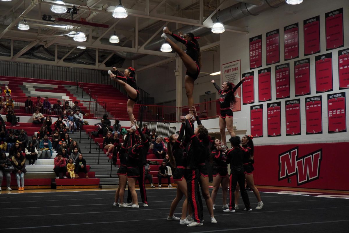 Niles West Varsity cheerleaders hold their teammates in the air as they pose. Niles West Varsity placed 3rd the Co-Ed division.