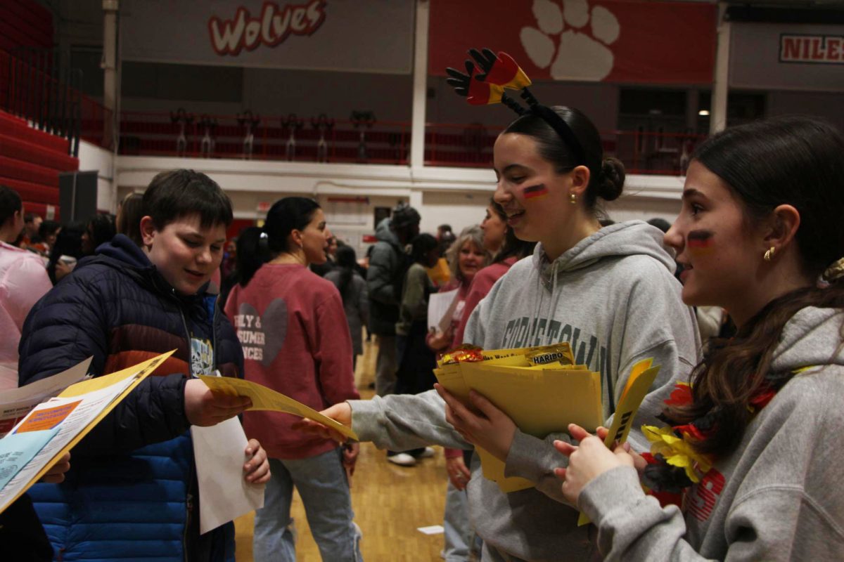 Sophomores Sara Pekovic and Antonia Schneider hand out flyers encouraging students to take  German with gummy bears while also having them guess words in German. 