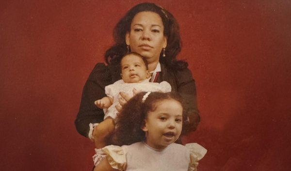 My grandma holding my aunt while my mom poses in front of them.