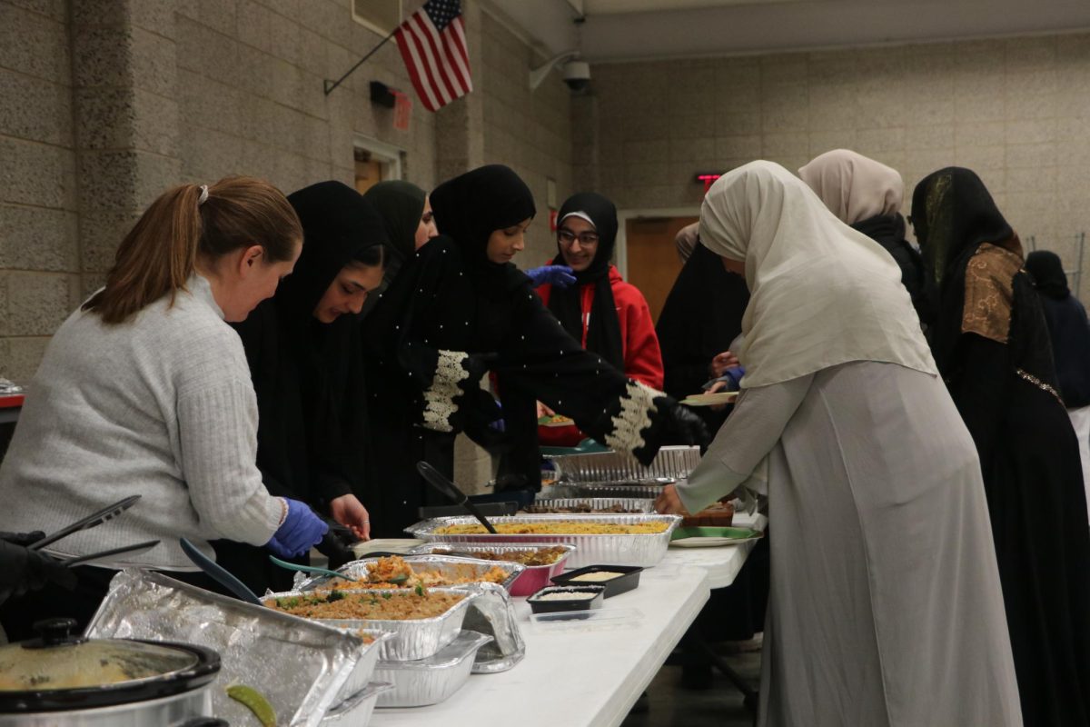 Students fill their plates with food made by community members. 