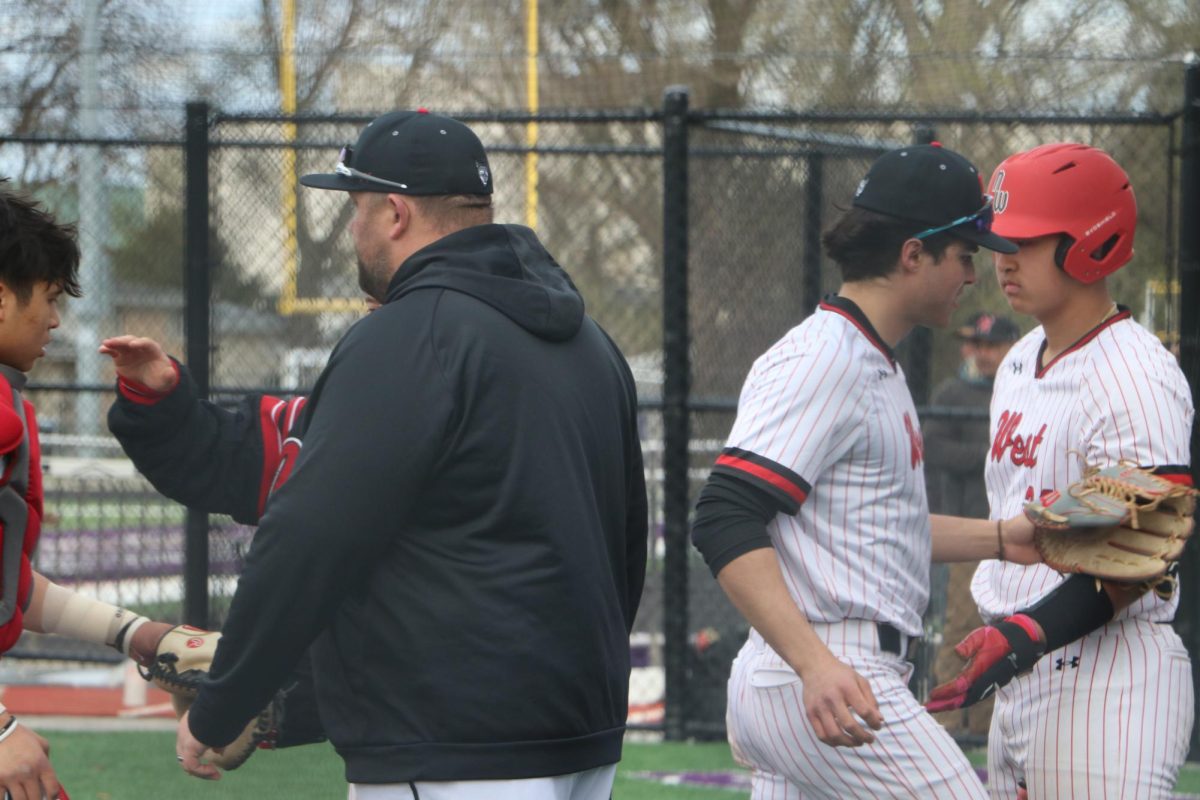 Coach Anthony Gliffe and senior Ryan Lee stand outside the dugout as the Wolves are come in from the infield to get ready for the next inning. 