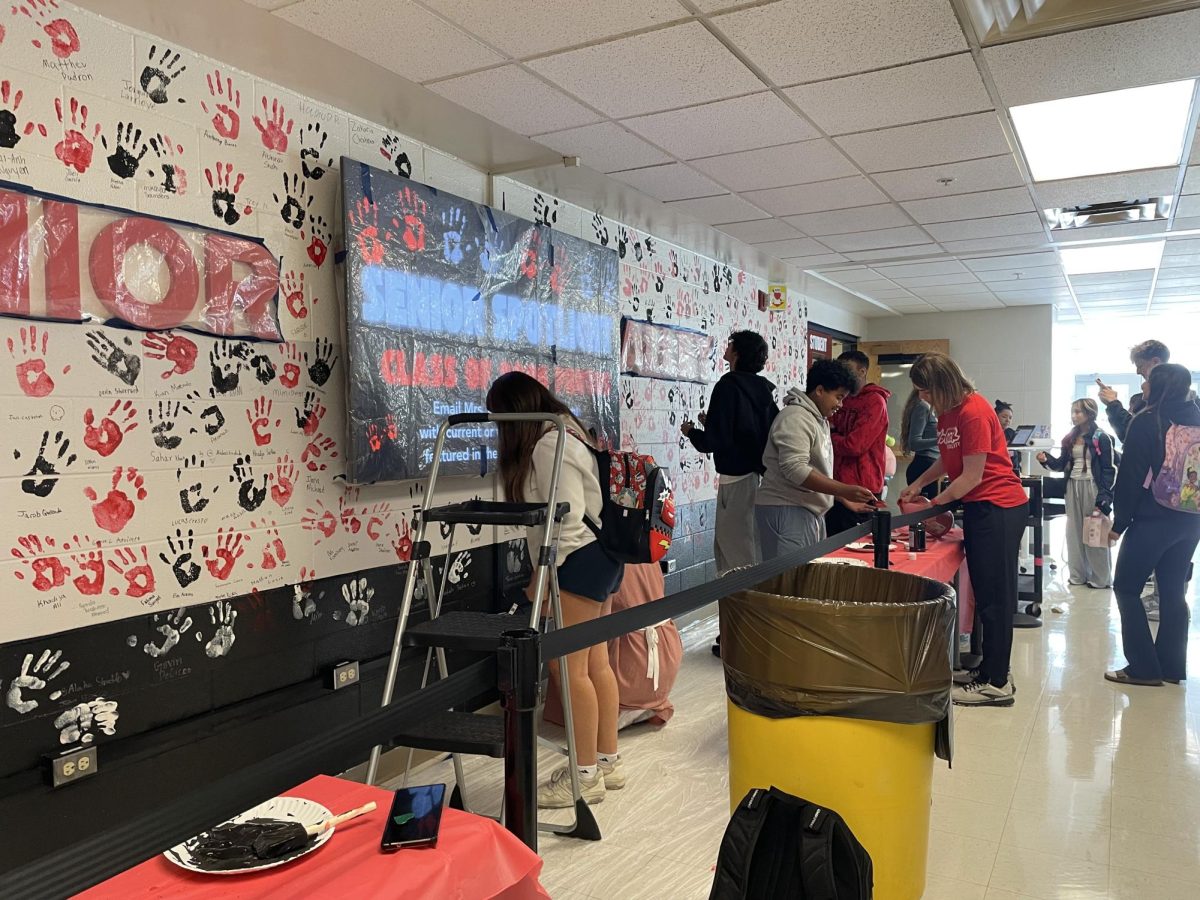 Seniors prepare as they imprint their handprints to the wall.