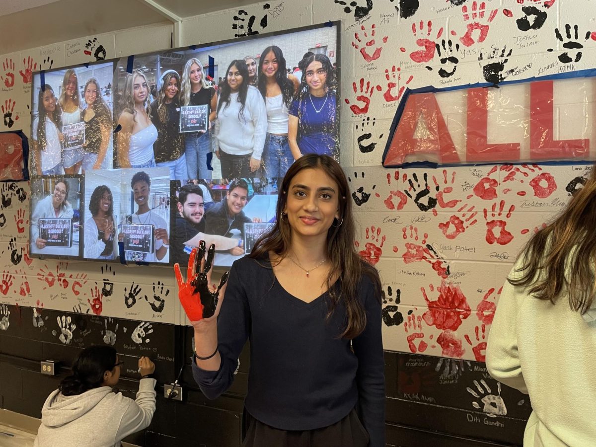 Maryam Adil, senior, joins in by adding her handprint to the wall.