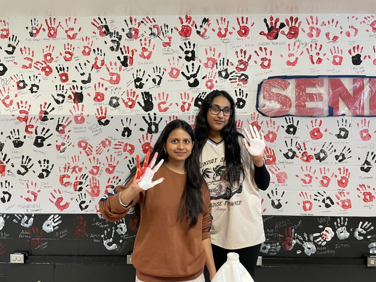 Banu Chand and Maryam Khan, seniors, gather to add their handprints to the wall as they share this special moment.