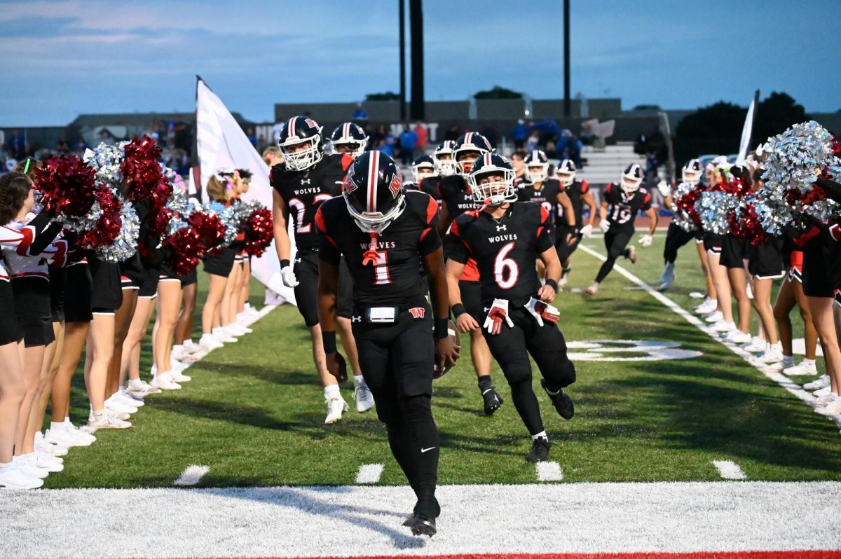 After the team warms up, the cheerleaders and dancers hold up the banner for the team to run through before the game starts. Starting quarterback Nick West, senior, leads his team through after breaking the banner while yelling for the team to get hype for the first home game of the season against Riverside-Brookfield. 