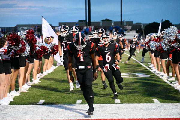 After the team warms up, the cheerleaders and dancers hold up the banner for the team to run through before the game starts. Starting quarterback Nick West, senior, leads his team through after breaking the banner while yelling for the team to get hyped for the first home game of the season against Riverside-Brookfield. 