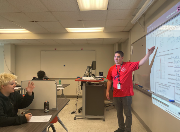 Michael Endo points at the projector as he helps a student. 