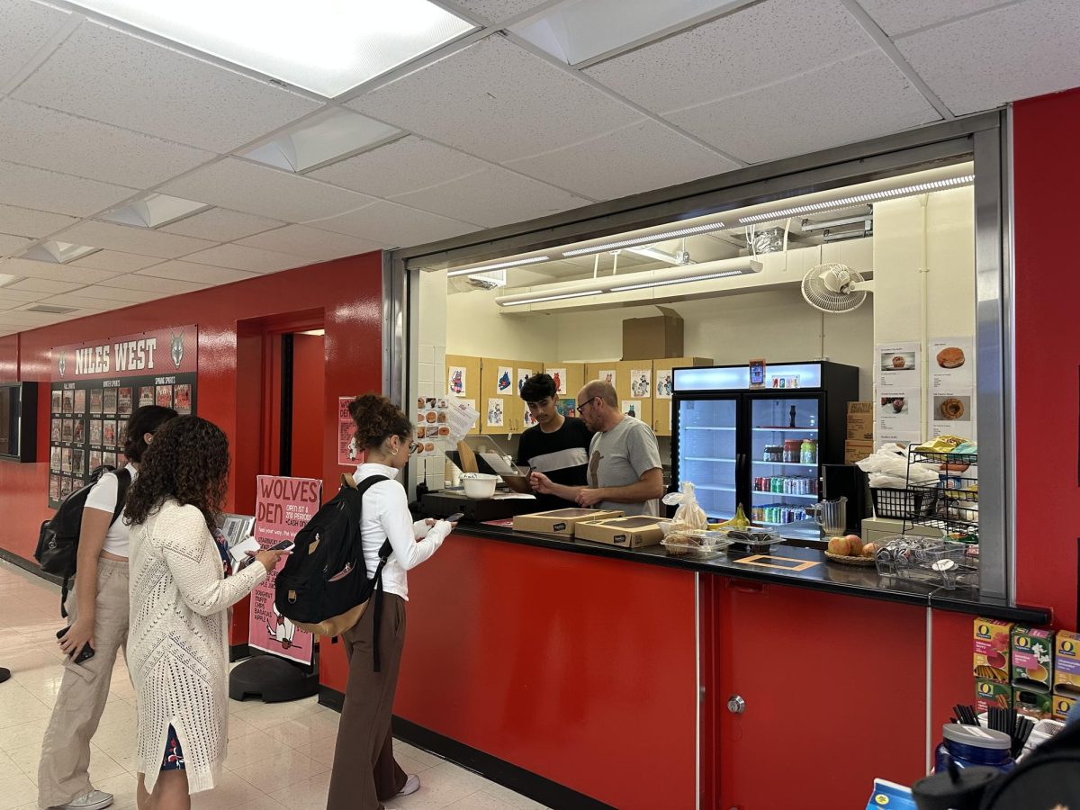 Students wait in line to purchase drinks and pastries from the Wolves Den while Landau helps a student employee.