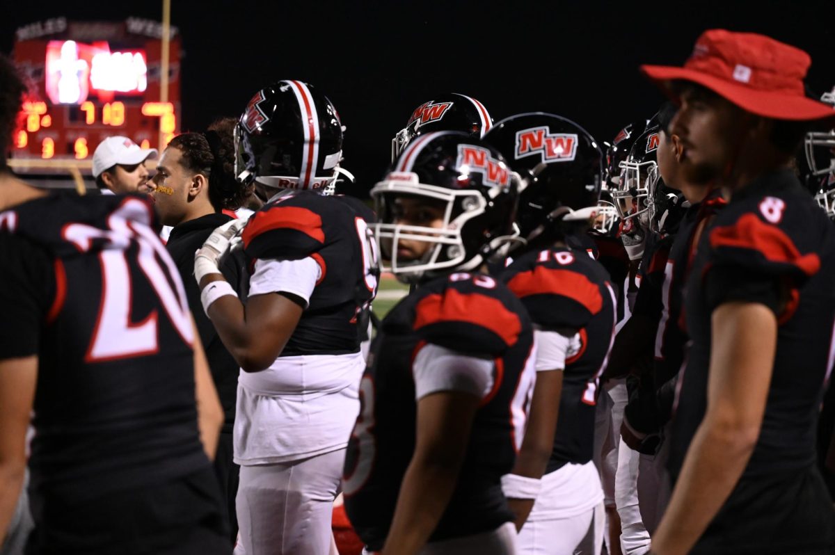 The team stands together on the side line watching the play on the field. 